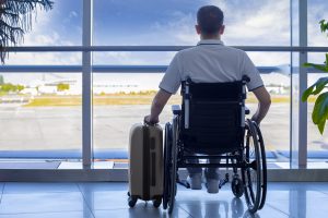 Young man in a wheelchair with luggage at the airport closeup