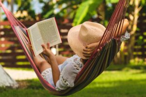Happy woman in white dress reading in hammock.