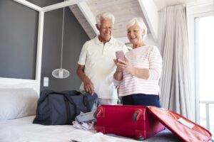 Senior Couple Look At Mobile As They Check In To Vacation Rental