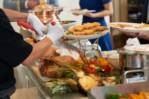 Gloved hands of waiter cutting turkey for the guests