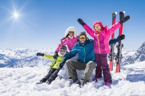 Happy family in winter holiday Laughing family in winter vacation with ski sport on snowy mountains. Happy man and woman with sons having fun and looking at camera. Family with two children enjoying winter holiday at ski resort.