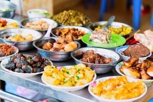 Assortment of exotic and delicious ready to eat foods in dishes on a tray.