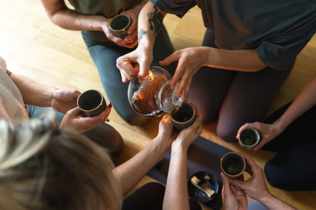 Group tea ceremony with herbal drinks during a wellness ritual, symbolizing grounding experiences for astrological travelers.