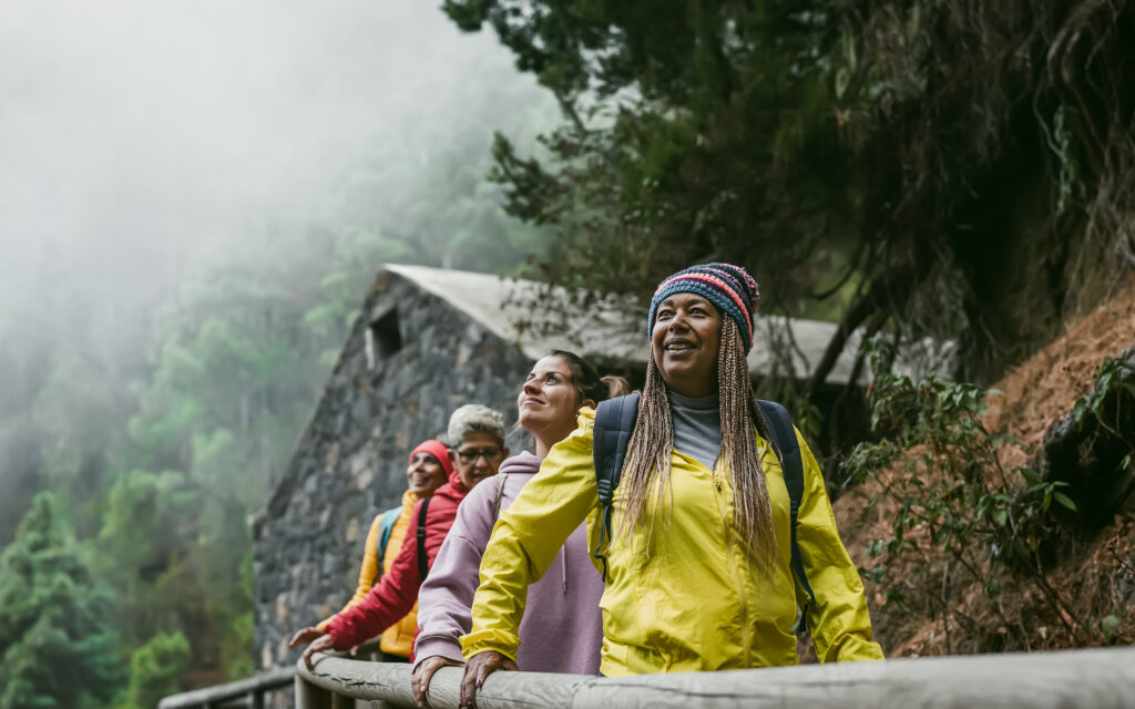 Group of diverse travelers hiking outdoors in the forest, reflecting the Blue Zone lifestyle of natural movement and active living.