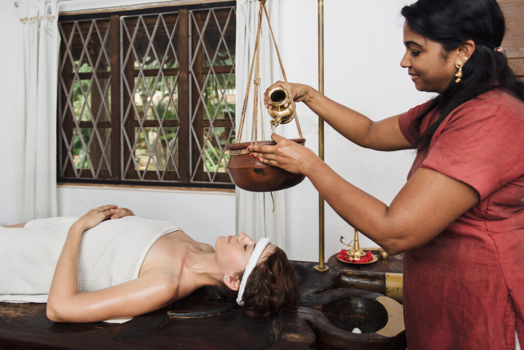 Woman having Ayurveda shirodhara treatment in India.