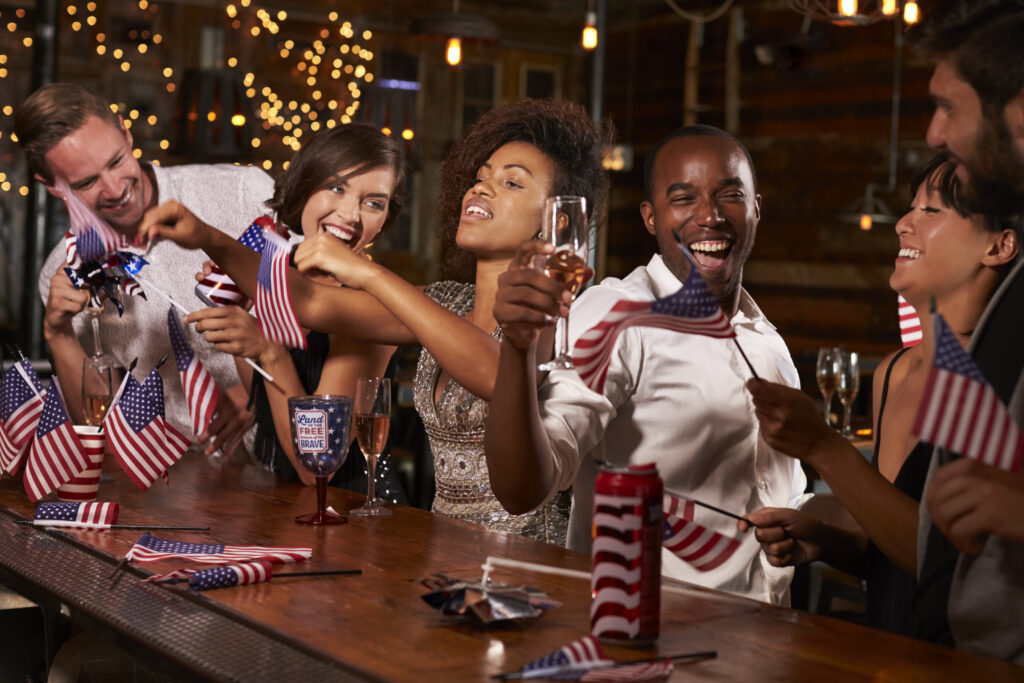 A group of friends at a bar, with champagne and American memorabilia, in celebration of the fourth of July - A great way to celebrate America's 250th.