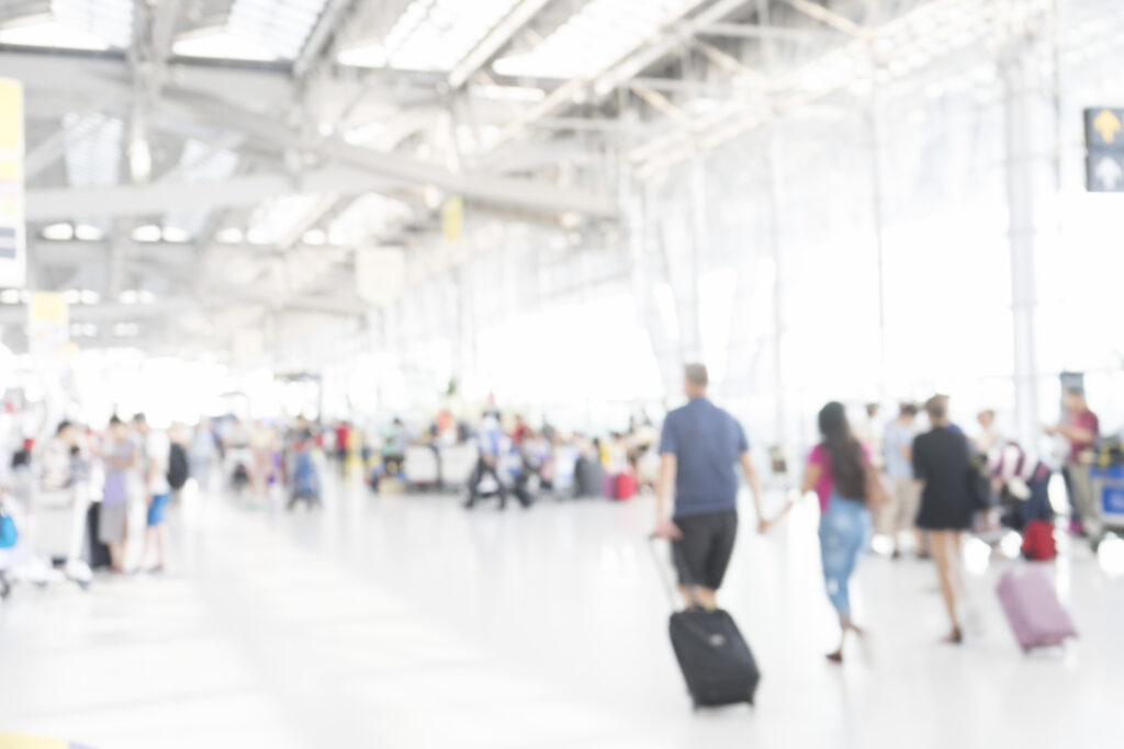 Event tourism travelers walking through the airport with their luggage.