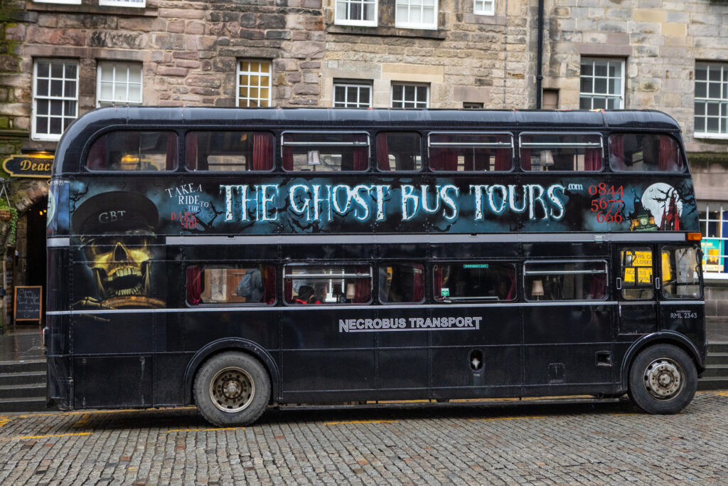 A large double decker black bus for the Ghost Bus Tours, a staple activity within dark tourism. 