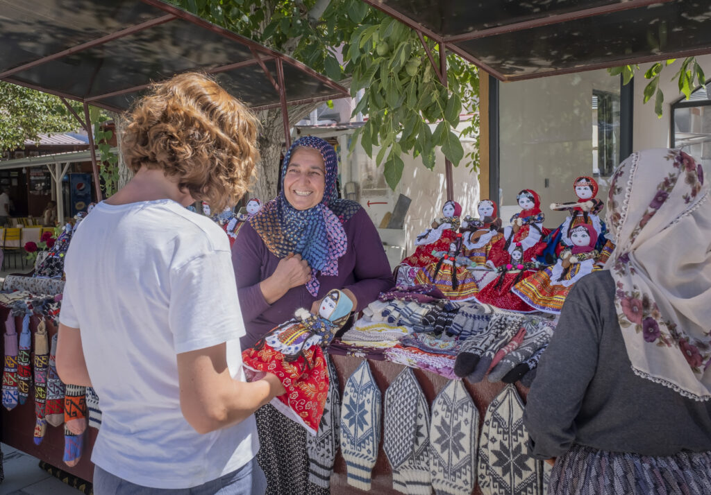 A woman shopping at a vendor stall selling handmade rag dolls.