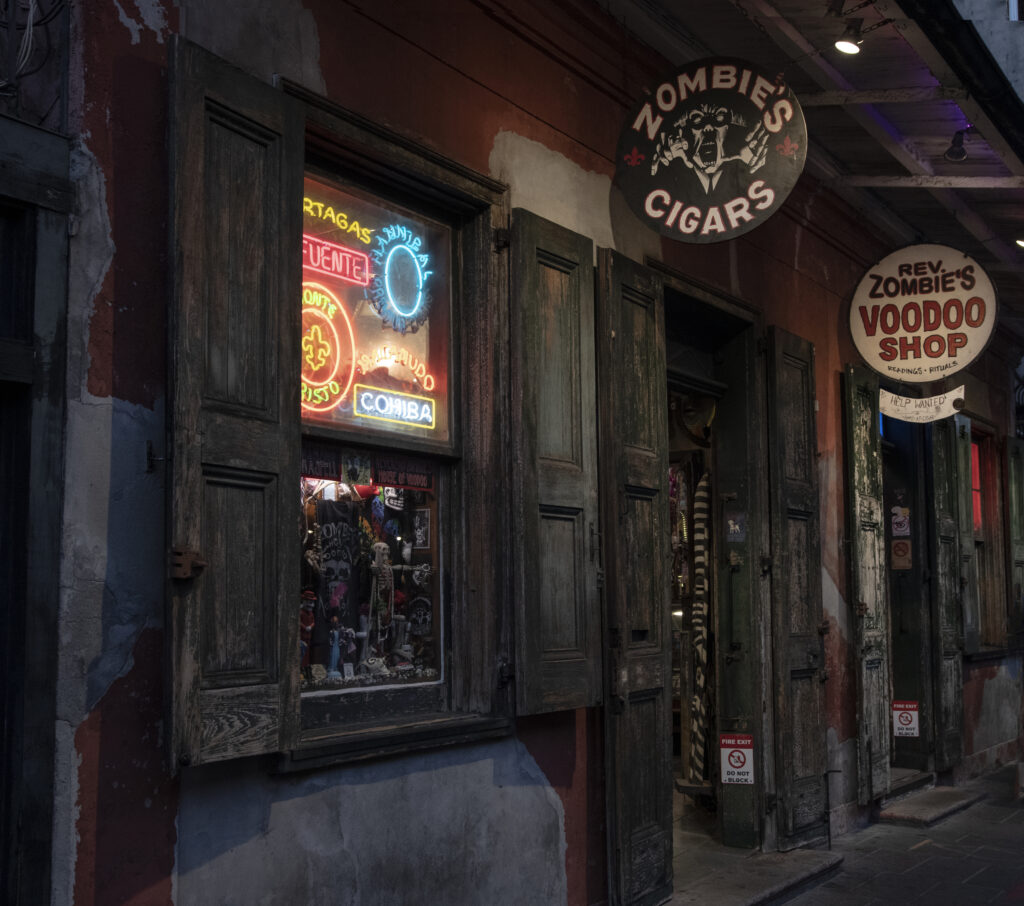 The outside of both a Zombie Cigar shop and a Zombie Voodoo shop that are worn down and aged, perfect for dark tourism. 