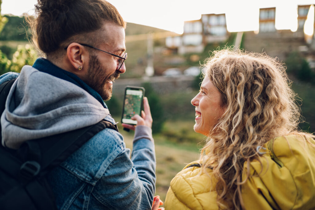 A close-up of a man and woman taking a photo of a scenic view in front of them while smiling at each other.
